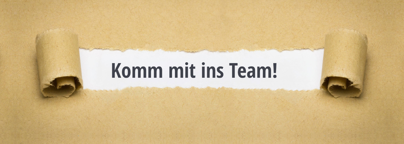 Aufgerolltes braunes Papier mit eingerissenem Mittelteil und dem Text 'Komm mit ins Team!'
