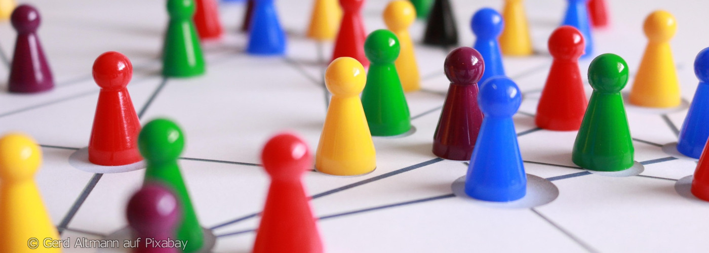 Mehrere bunte Spielfiguren stehen auf einem weißen Spielfeld, das durch Linien in Felder unterteilt ist