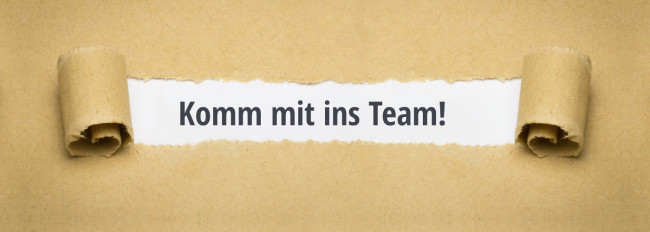 Braunes Papier mit eingerissenem Mittelteil, sichtbar der Text 'Komm mit ins Team!' in schwarzer Schrift